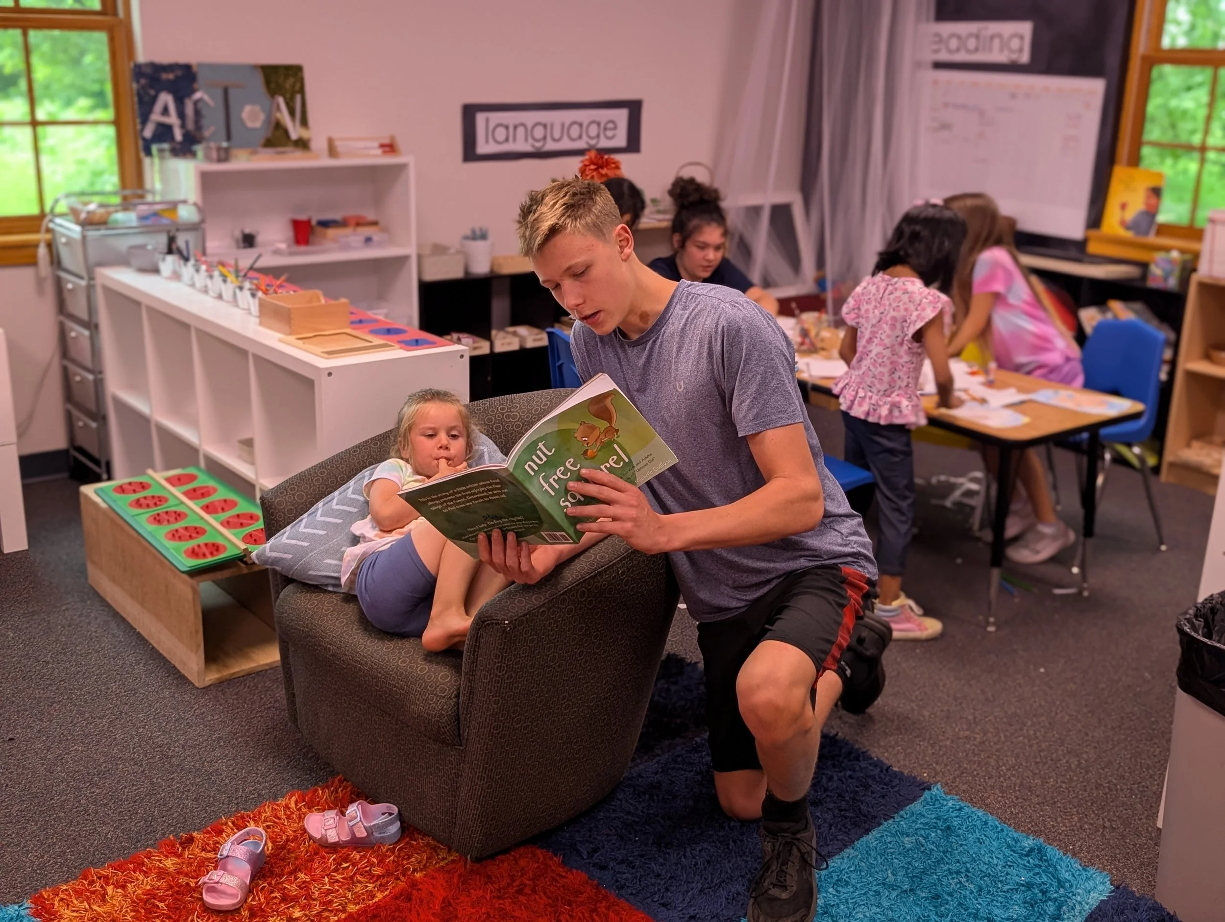 Montessori-Inspired Microschool Middle School Student reading to younger peer